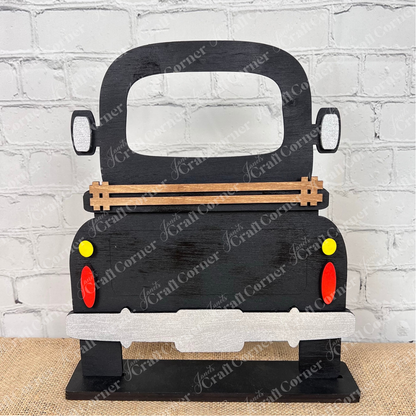 The Antique Truck Interchangeable Base  Standing DIY home decor kit by Janet's Craft Corner features wooden cutout pieces which have been painted black, displayed on a white brick background.