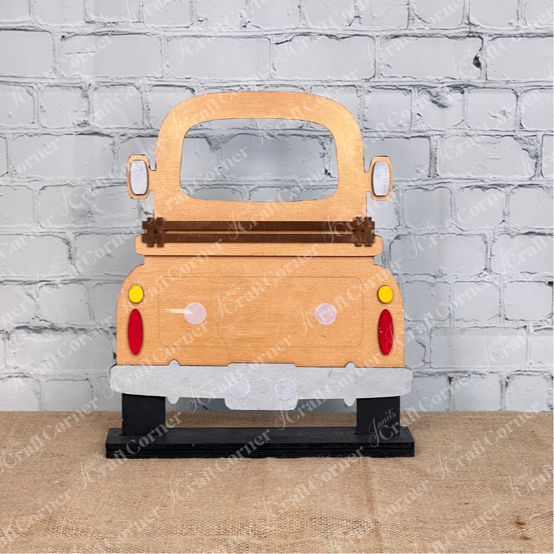The Antique Truck Interchangeable Base  Standing DIY home decor kit by Janet's Craft Corner features wooden cutout pieces which have been painted copper, displayed on a white brick background.