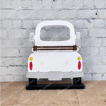 The Antique Truck Interchangeable Base  Standing DIY home decor kit by Janet's Craft Corner features wooden cutout pieces which have been painted white, displayed on a white brick background.