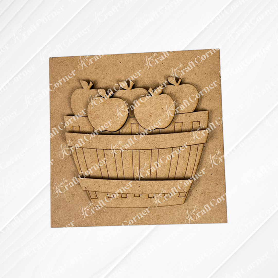 Janet's Craft Corner Apple Basket Square features a square wood piece with a raised, laser-cut basket of five apple cut-outs on a textured, painted white background—ideal unfinished DIY home decor.