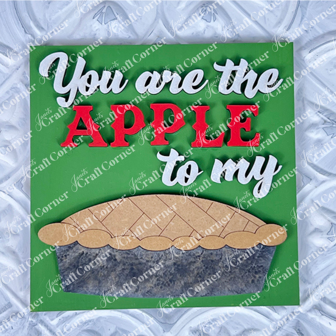 Janet's Craft Corner’s Apple Pie Square sign features “You are the APPLE to my” in white and red on green, above a wooden pie cut-out – a charming, DIY-ready home decor piece.