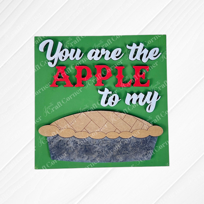 Janet's Craft Corner’s Apple Pie Square sign features “You are the APPLE to my” in white and red on green, above a wooden pie cut-out – a charming, DIY-ready home decor piece.