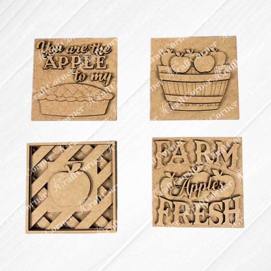 Janet's Craft Corner Apple Swappable Squares DIY kit includes four wooden signs with apple cut-outs: "You are the apple to my pie," a basket, a striped apple, and "Farm Fresh Apples." Perfect for seasonal home decor.