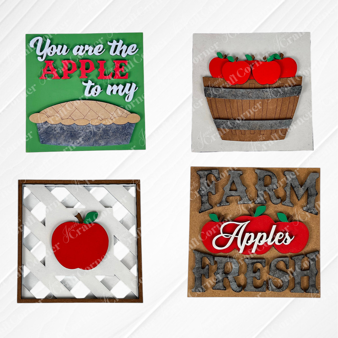 Janet's Craft Corner Apple Squares features four farmhouse-style wood signs with apple designs, displayed on a white wood background.