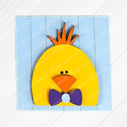 A cartoon-style yellow chick with an orange beak, spiky crest, and purple bow tie stands on a light blue wooden background—perfect for adding to your Hello Easter Squares kit from Janet's Craft Corner.