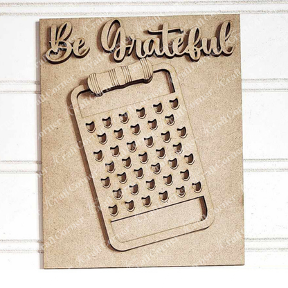 Janet's Craft Corner Kitchen Switchable Farmhouse Signs is a DIY home decor kit featuring a light wood “Be Grateful” sign with a box cheese grater cutout—perfect rustic kitchen accent, displayed on a white textured background. Set of 1.