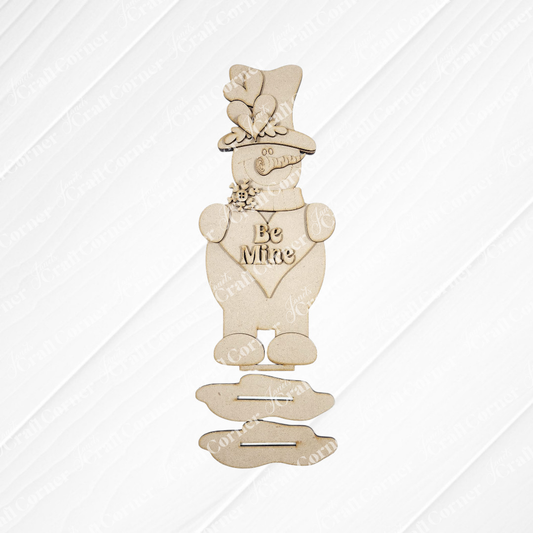 Janet's Craft Corner Be Mine Snowman Shelf Sitter DIY kit features a smiling figure with a heart reading "Be Mine," hat with butterfly and flowers, and separate base pieces—perfect for holiday decorating or seasonal home decor. Set of 1.