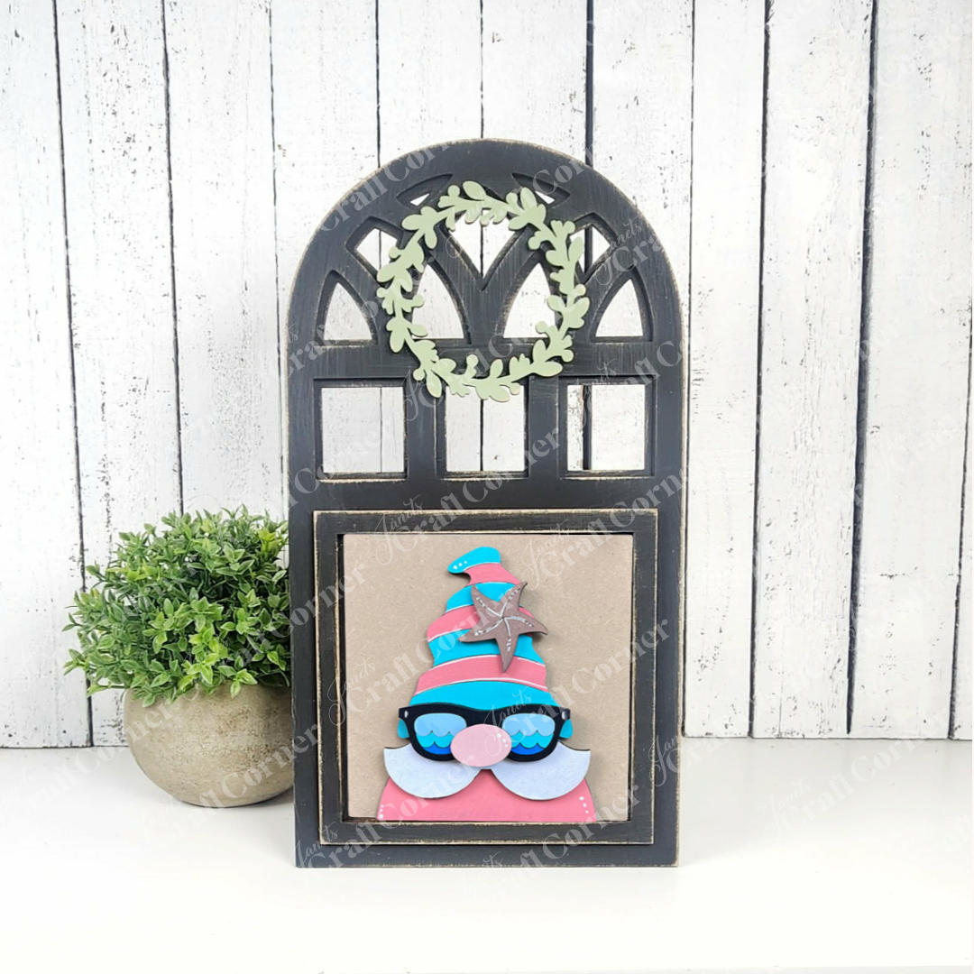 Janet's Craft Corner’s Summer Lovin Swappable Squares DIY craft kit features a wooden arch frame with a small green wreath and fun gnome art, plus a potted plant—perfect tiered tray decor for summer against white wood paneling.