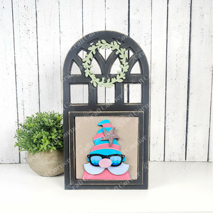 Janet's Craft Corner’s Summer Lovin Swappable Squares DIY craft kit features a wooden arch frame with a small green wreath and fun gnome art, plus a potted plant—perfect tiered tray decor for summer against white wood paneling.
