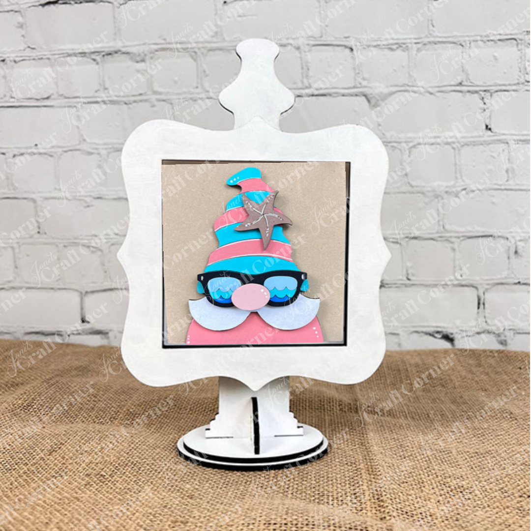 The Summer Lovin Swappable Squares DIY craft kit from Janet's Craft Corner features a colorful gnome with sunglasses, pink hat, and silver star on a white decorative frame—ideal for tiered tray decor or pairing with wood cut-outs.