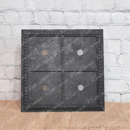 The Heartland Bead Trim Swappable Squares Frame, a square black frame with four sections and circular cutouts, sits on a textured surface before a white brick wall—perfect for DIY craft kits or customizable square signs.