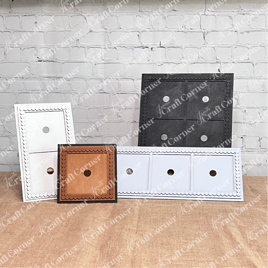 Heartland’s Bead Trim Swappable Squares Frame set includes four square and one rectangular frame in white, brown, and black—each with a central circular cutout—displayed upright on burlap against a white brick wall. Perfect for DIY crafts.