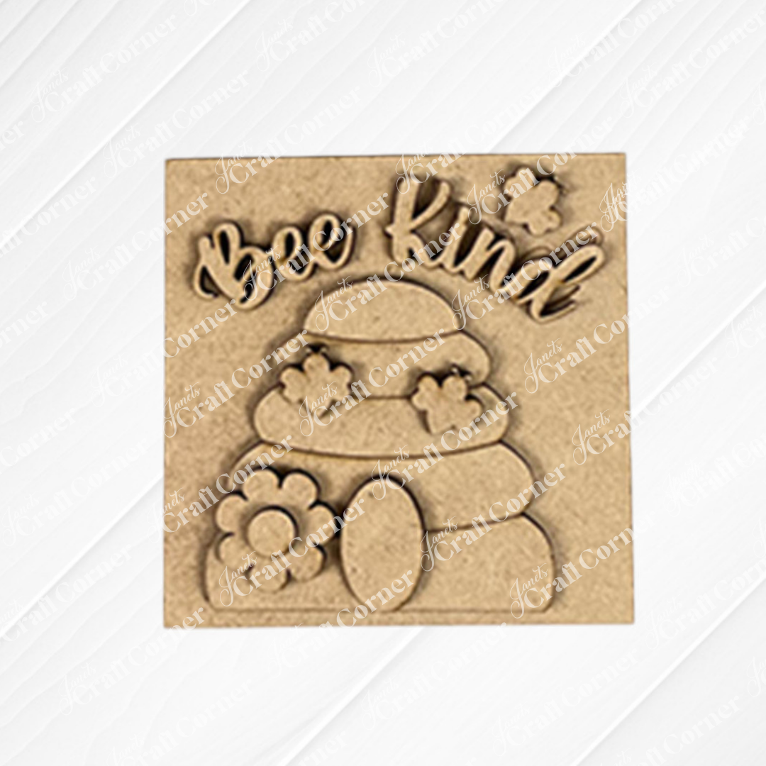 The Bee Swappable Squares by Janet's Craft Corner features "Bee Kind" above a beehive with flowers and a bee, handmade for charming home decor on a textured white background.