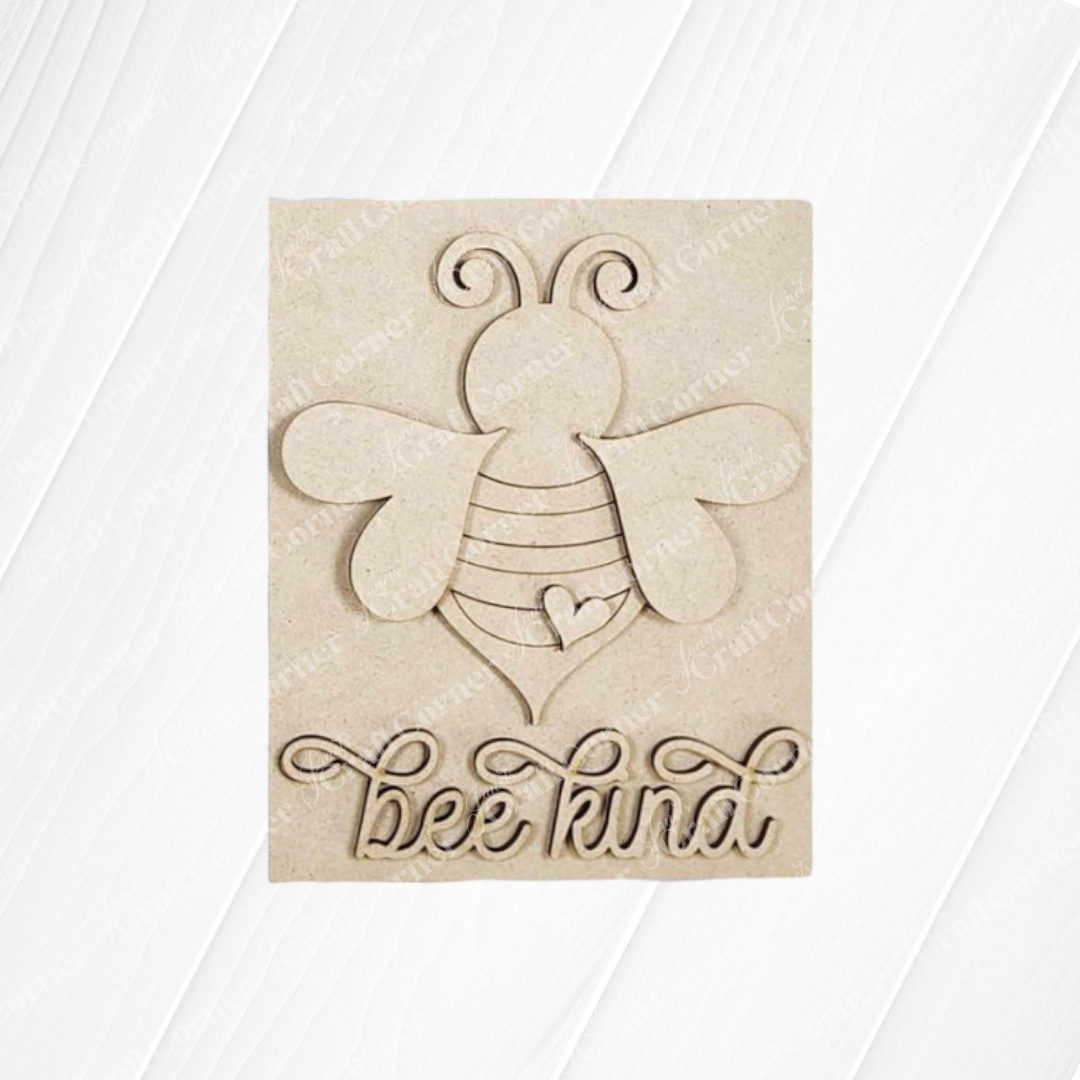 The Bee Kind Farmhouse Sign from Janet's Craft Corner features a carved wooden plaque with a stylized bee, swirly antennae, and a heart-shaped body. "Bee Kind" is intricately cut out in cursive below, set against a subtle wood grain texture for charming decor.