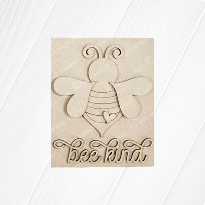 The Bee Kind Farmhouse Sign from Janet's Craft Corner features a carved wooden plaque with a stylized bee, swirly antennae, and a heart-shaped body. "Bee Kind" is intricately cut out in cursive below, set against a subtle wood grain texture for charming decor.