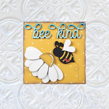 Bee Swappable Squares by Janet's Craft Corner: A handmade card with a bee and daisy on yellow, blue "bee kind" script, white dots, and embossed border—charming for gifts or cheerful decor.