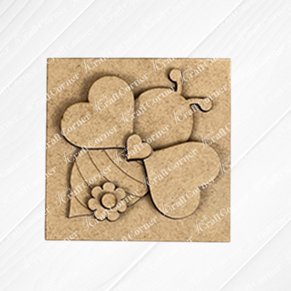 The Bee Swappable Squares by Janet's Craft Corner features a heart-winged, striped bee with a flower accent, adding handmade charm as delightful home decor on a textured white surface.