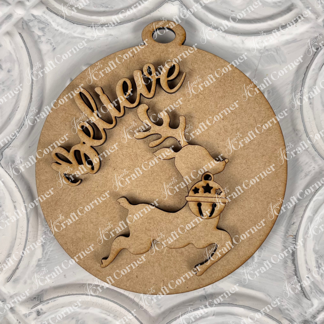 Introducing Janet's Craft Corner's "Round Christmas Ornaments | DIY Decoration Kits": A delightful round wooden ornament showcasing a reindeer silhouette and the word "Believe" elegantly cut out. Its textured, decorative pattern in soft light gray tones makes it a perfect addition to your holiday decor and an ideal piece for any Christmas ornaments collection.