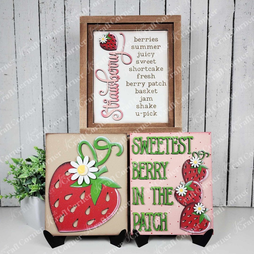 Janet's Craft Corner – Sample painted set of Berry Sweet Switchable Farmhouse Sign is a DIY seasonal home decor kits with a strawberry theme, one features the word Strawberry with a red berry and words that evoke a trip to the berry patch, another features a large strawberry and the final one features the words “Sweetest Berry in the Patch” and a stack of 3 berries.