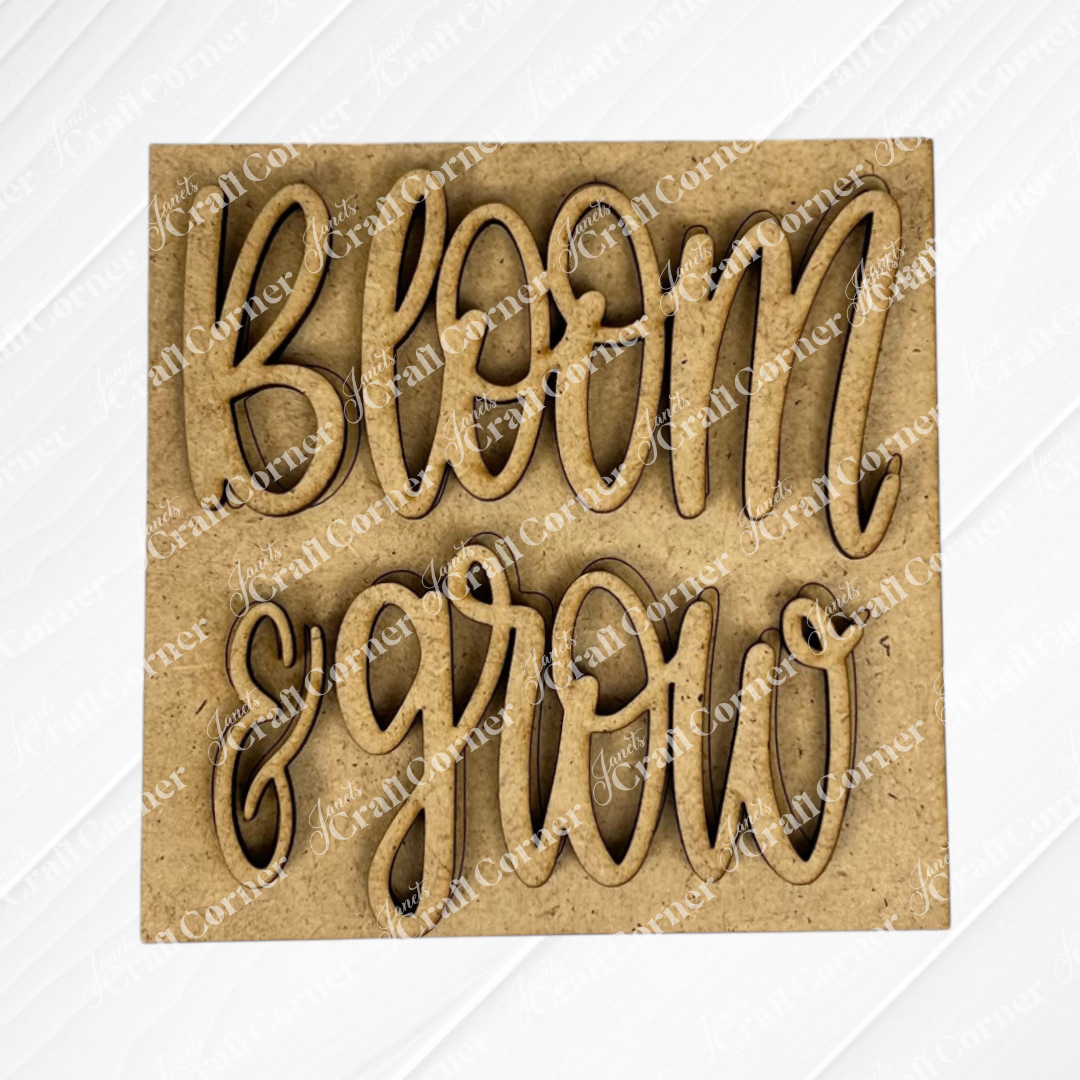 The Bloom & Grow Squares by Janet's Craft Corner features a laser-cut, light brown wood sign with "bloom & grow" in cursive and a subtle white diagonal pattern—perfect for tiered tray decor or Swappable Squares displays.