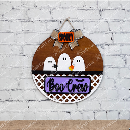 The Boo Crew Interchangeable Insert from Janet's Craft Corner features three cartoon ghosts and a black spider with a "Spooky" banner and "Boo Crew" on a purple label. Designed with a lattice pattern, it fits seamlessly as an insert for festive displays.