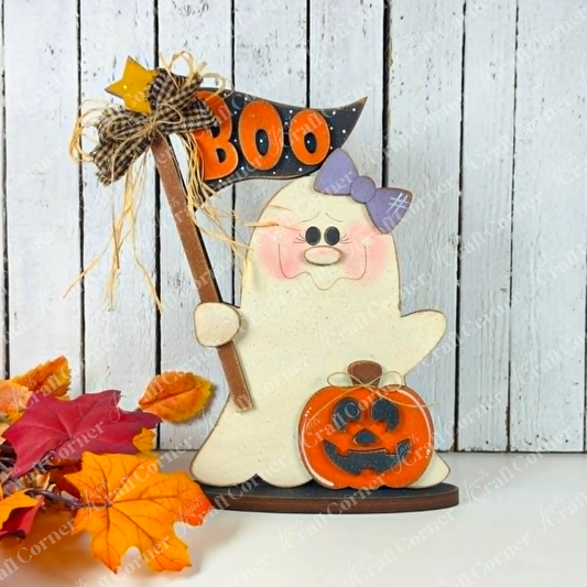 Add a playful touch to your spooky-cute décor with the Boo Ghostie Shelf Sitter DIY home decor craft kit from Janet’s Craft Corner. This adorable Halloween shelf sitter features a ghost with a purple bow holding a “BOO” sign, standing beside a cheerful jack-o’-lantern. Autumn leaves are scattered at its feet, all set against a rustic white wooden background – perfect for brightening up your festive display!.