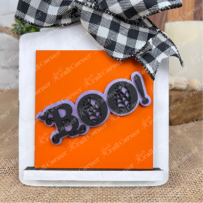 Janet's Craft Corner's Halloween Squares features wood cut-outs, a black and white checkered bow, and an orange "Boo!" sign with spider web details—perfect for tiered tray decor.