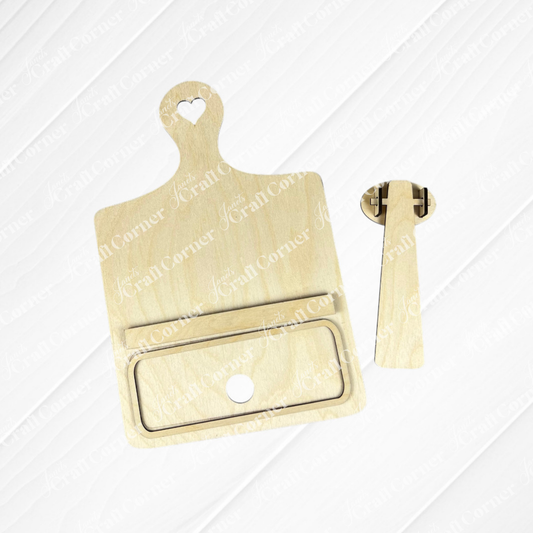 MDF pieces are displayed on a white background, crafted as part of the "Breadboard Classic Interchangeable Base" DIY home decor kit by Janet's Craft Corner. One piece resembles a cutting board with a heart-shaped hole at the top and a rectangular slot, while the other is a stand component designed for the back of the board.