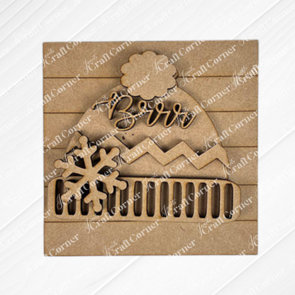 Add a charming touch to your decor with Janet's Craft Corner "Hello Winter Squares"—a laser-cut wooden ornament shaped like a winter hat with "Brrr," snowflake detail, and textured stripes, perfect for tiered trays or seasonal displays.