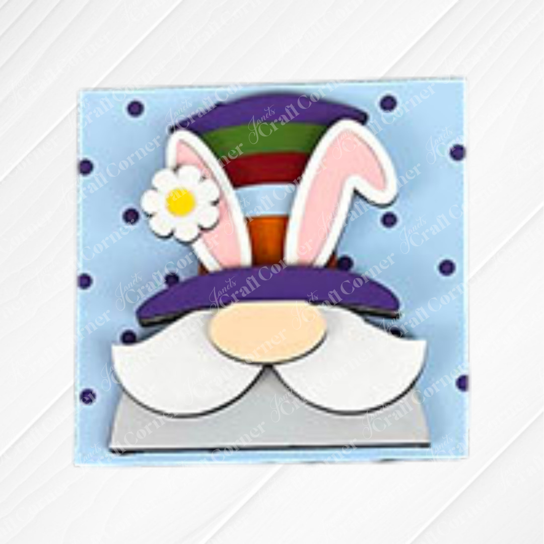 Cartoon bunny with big pink ears, a striped purple hat with a white flower, and a white mustache on a blue polka-dot background—great for wood cut-outs or the Hello Easter Squares DIY craft kit by Janet's Craft Corner.
