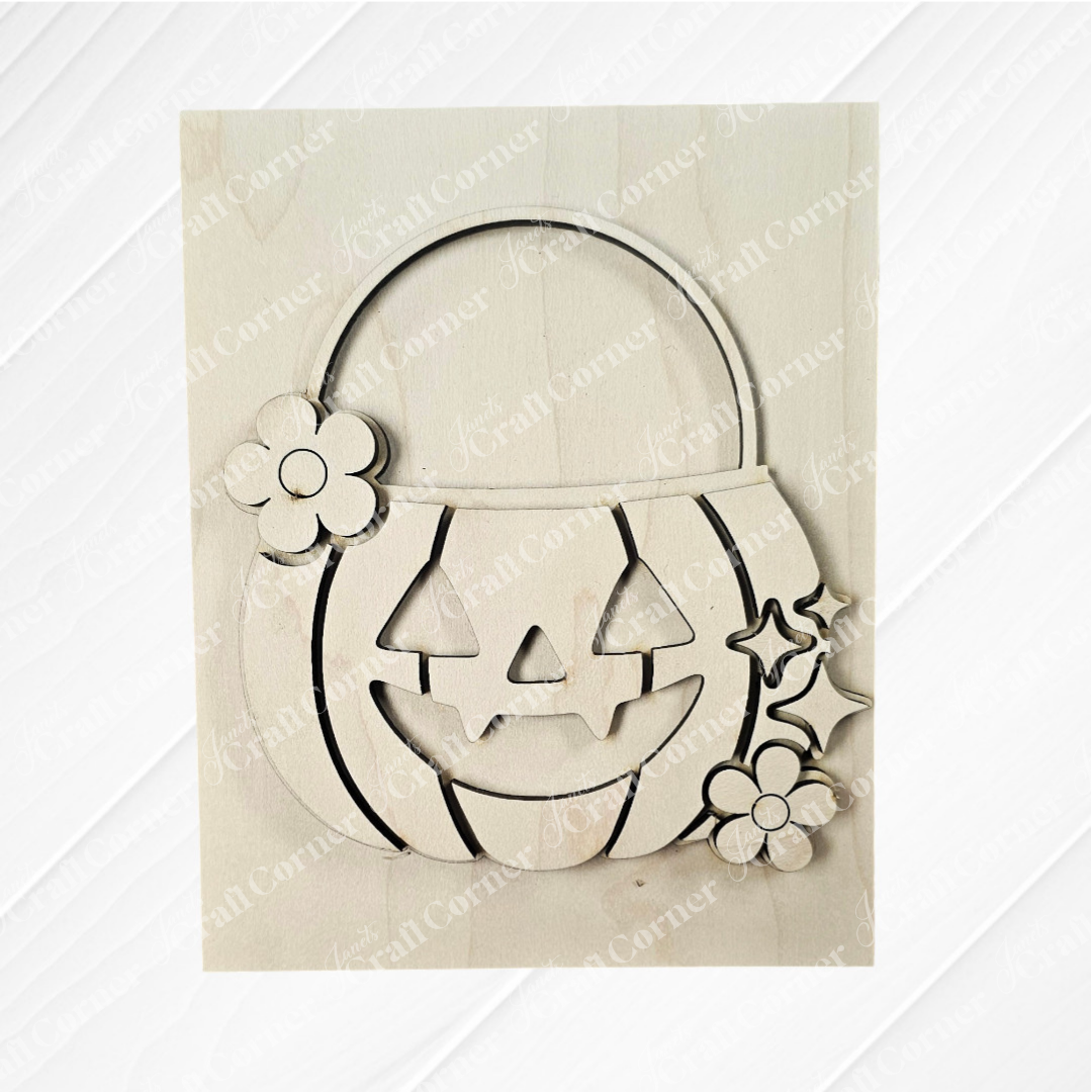 The Halloween Farmhouse Signs from Janet's Craft Corner feature a wooden jack-o'-lantern cutout with smiling face, floral accents, and handle—perfect DIY seasonal home decor for your tiered tray, shown on a light wooden background.