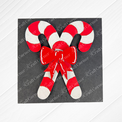 Two red and white striped candy canes crossed with a red bow on a dark background—just one design from Janet's Craft Corner’s Christmas Icon Swappable Squares DIY home decor kit, perfect for festive seasonal sign crafts.