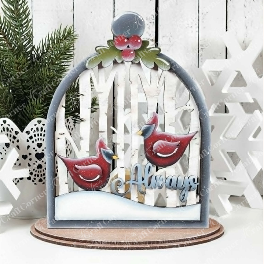 Bring a touch of winter charm to your home with the Cardinal Cloche Votive Holder Shelf Sitter DIY craft kit from Janet’s Craft Corner—a single wooden ornament featuring two red cardinals perched among birch trees, pine branches, and delicate snowflake details on a rustic white background with “Always” inscribed below. Perfect for cardinal-themed home décor or as an inspiring DIY project.