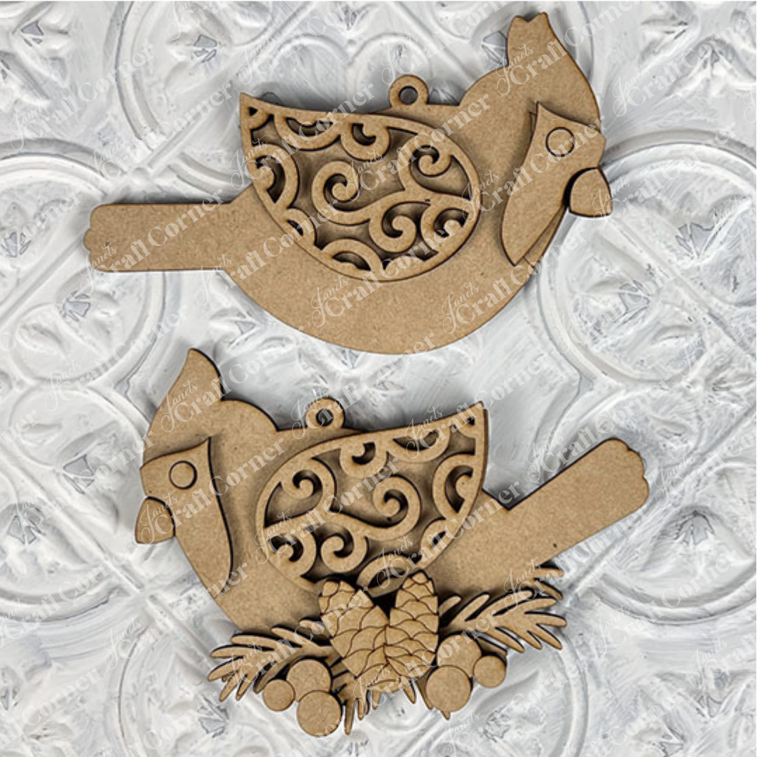 The Cardinal Ornament DIY craft kit from Janet's Craft Corner offers two design choices and includes a set of one. Perfect for holiday décor, these ornaments feature intricate swirls on their wings, a hanging loop, and embellishing pinecones and leaves for festive charm.