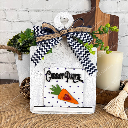 The Easter Bunny Squares by Janet's Craft Corner are decorative white wooden signs with heart cutouts, zigzag bows, greenery, and "Carrot Patch" text—perfect wood cut-outs or tiered tray decor for a rustic table setting.