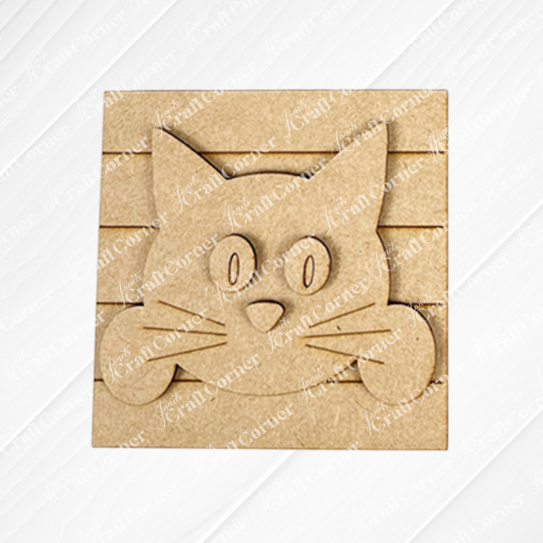 The Cat Swappable Squares by Janet's Craft Corner features a wooden cartoon cat face with big oval eyes, pointy ears, and whiskers on a grooved square—ideal for tiered trays or DIY seasonal home decor projects.