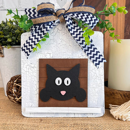 Janet's Craft Corner Cat Swappable Squares feature a black cat wood cut-out with a pink nose, set on brown with blue-and-white chevron ribbon and greenery—ideal DIY home decor for any season against distressed white wood.