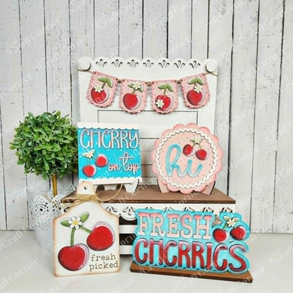 Janet's Craft Corner Cherry Decor Set features wooden farmhouse-style signs with cherry designs and messages like "CHERRY on top," plus a cherry garland, all displayed on a white chair—perfect for DIY home decor enthusiasts.