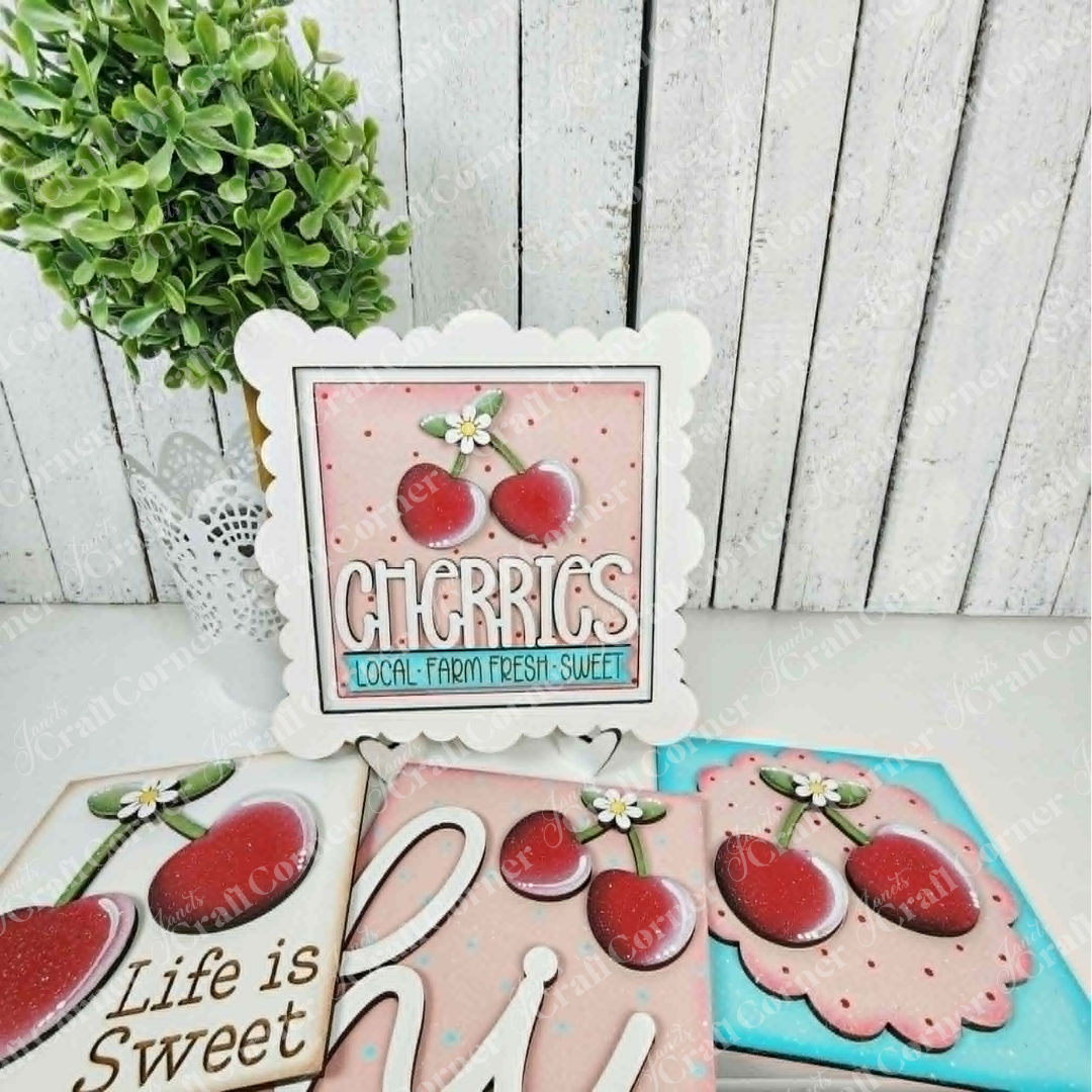 Cherry Squares - DIY seasonal home decor craft kit by Janet's Craft Corner features decorative wood cut-outs with cherry designs and messages like "Cherries Local Farm Fresh Sweet," "Life is Sweet," and "Hi"—perfect for tiered tray displays.