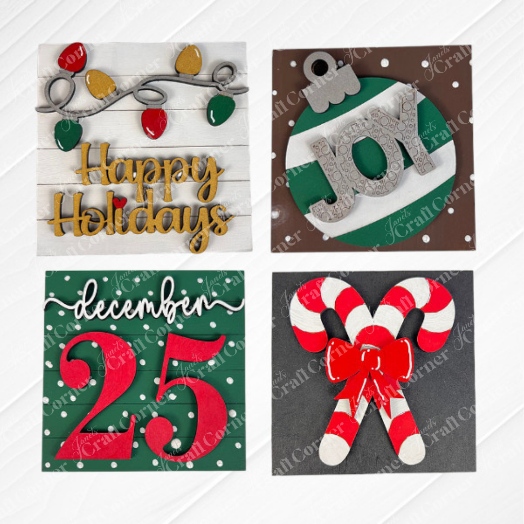 Janet's Craft Corner Christmas Icon Swappable Squares DIY kit includes four festive designs: string lights with "Happy Holidays," a green ornament with "JOY," snowy "December 25" script, and crossed candy canes—perfect for seasonal home decor.