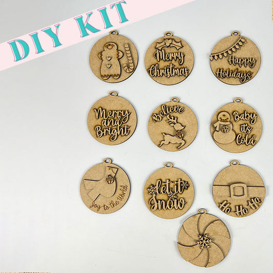 The Round Christmas Ornaments DIY Decoration Kit from Janet's Craft Corner includes laser-cut wooden ornaments adorned with festive designs and phrases such as "Merry Christmas," "Believe," and "Let it Snow." Perfect for holiday decorating, each ornament features a small hanging hole at the top.