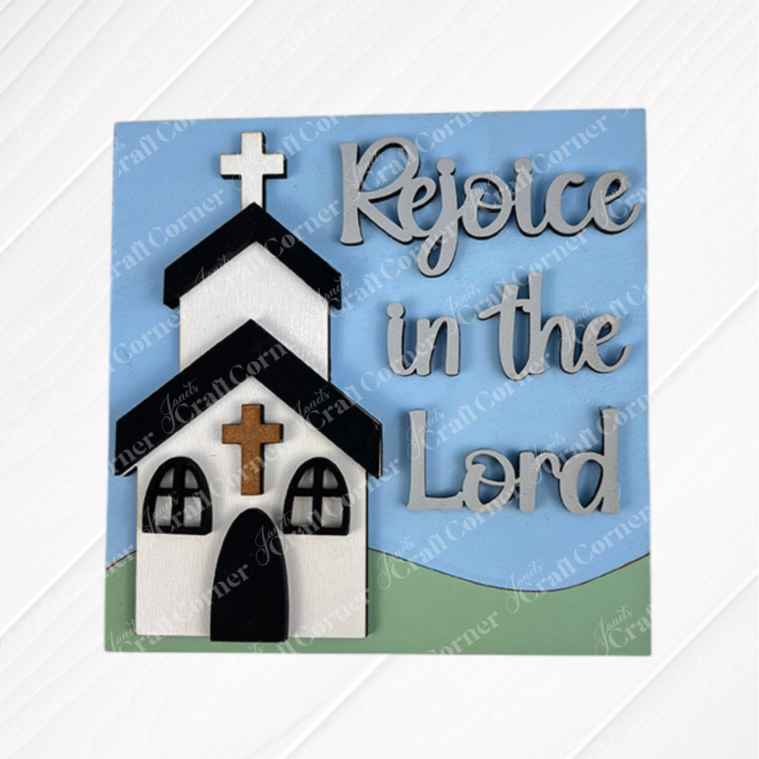 Janet's Craft Corner Religious Easter Squares: A decorative sign with wood cut-outs of a white church and cross, "Rejoice in the Lord" in raised cursive, perfect tiered tray decor with a blue sky and green hill background.
