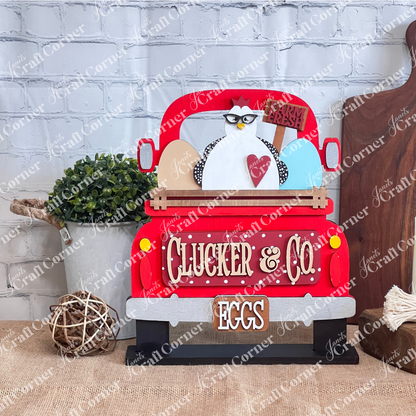 A decorative sign from Janet's Craft Corner, the Clucker & Co. Interchangeable Insert - Painted, features a vintage truck design with a charming chicken motif sporting glasses. The truck is adorned with the "Clucker & Co." and "EGGS" labels, highlighted by a heart symbol and three large eggs beneath a "Farm Fresh" banner, adding rustic charm to any space. This piece elegantly brings interchangeable craft inserts to life.