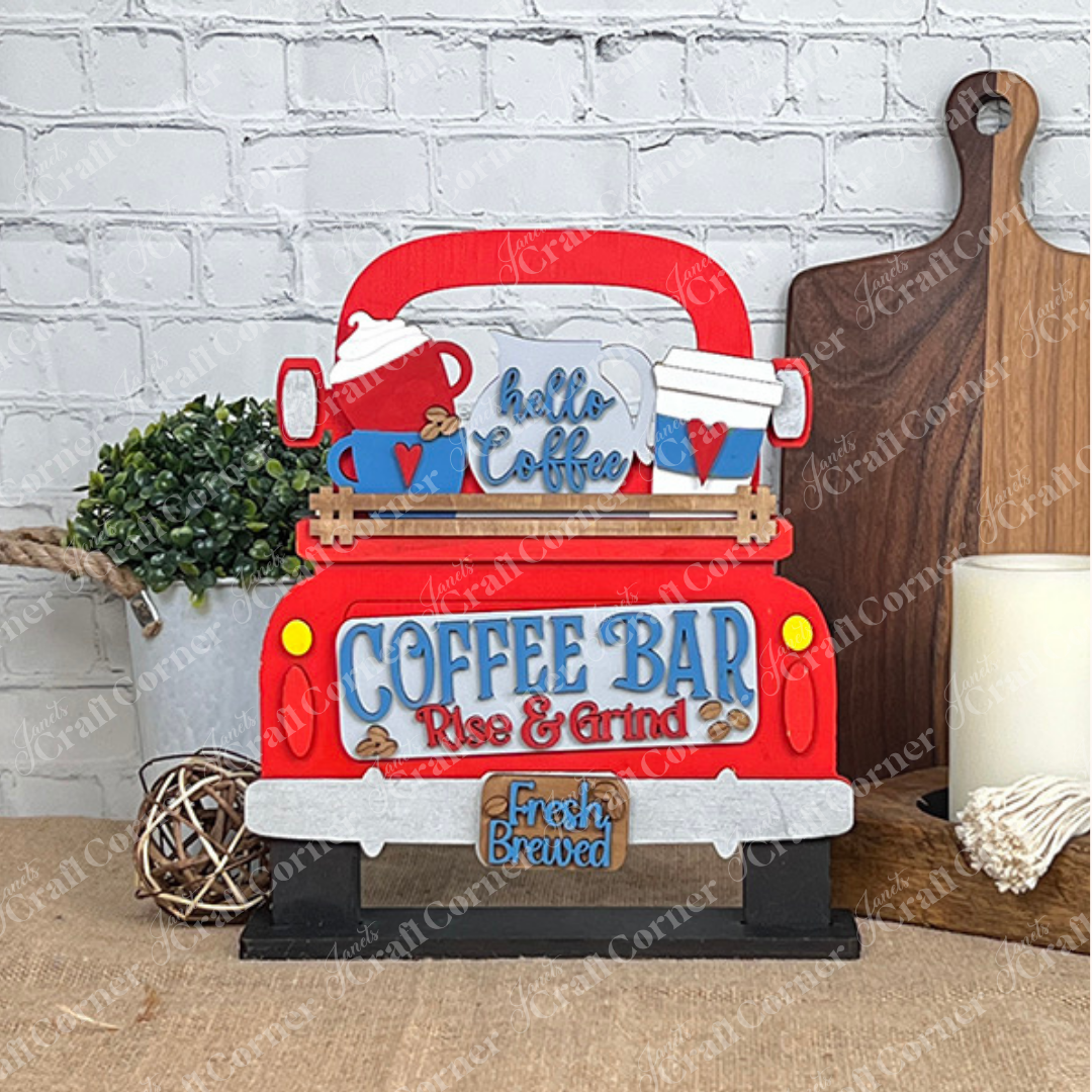 The Coffee Bar Interchangeable Insert from Janet's Craft Corner showcases a decorative red truck sign with "Coffee Bar, Rise & Grind" in vibrant blue and red letters. On the back, two coffee mugs are nestled—one in red and the other in white adorned with hearts. Below, a "Fresh Brewed" sign is included, making it an ideal addition as a Coffee Bar Insert amidst plants and cutting boards in your home decor.