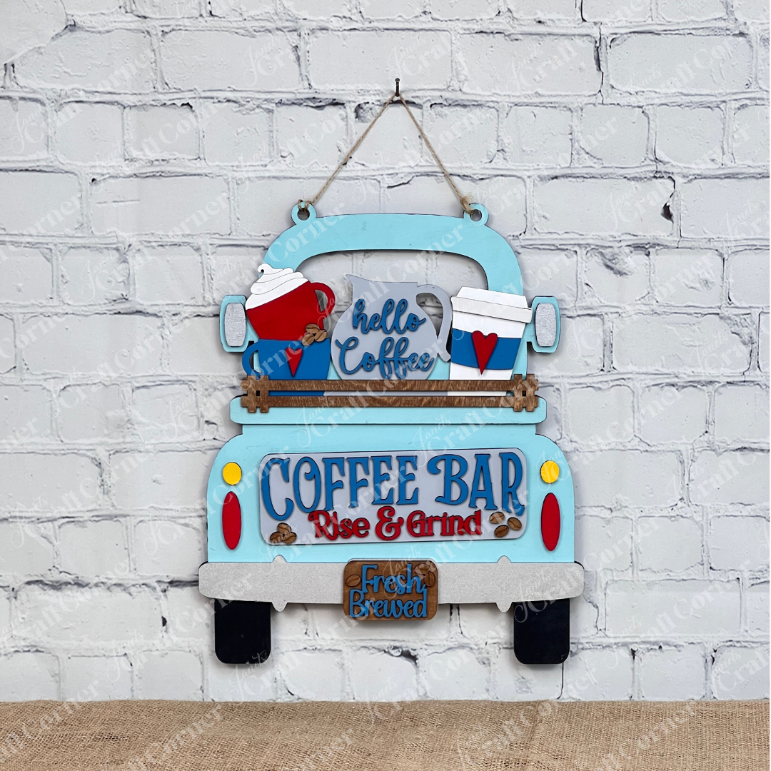 This charming home décor piece, by Janet's Craft Corner, features an antique truck base with a DIY interchangeable wooden red truck insert. Decorated with "Coffee Bar" and "Fresh Brewed" signs, coffee mugs, and hearts against a white brick wall, it's surrounded by cutting boards, a plant, and a candle.