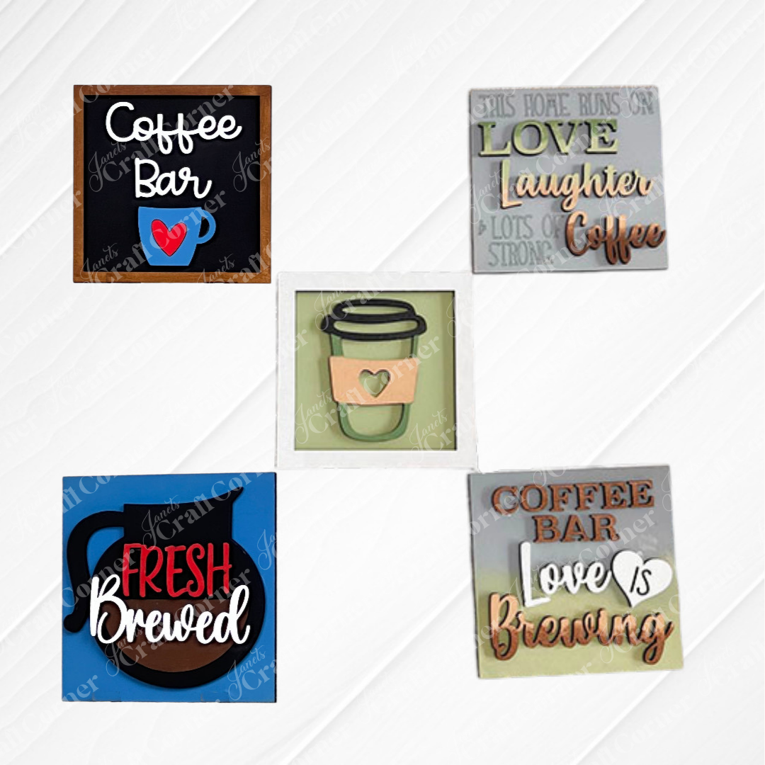 Set of five "Coffee Bar Swappable Squares" by Janet's Craft Corner—square wooden plaques with coffee-themed designs like "Love, Laughter, Coffee" painted in neutral and bright colors. Ideal for DIY home decor or adding charm to small spaces. Displayed on a white background.