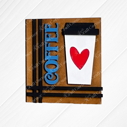 Celebrate coffee lovers with Janet's Craft Corner Coffee Swappable Squares—a DIY seasonal home decor kit featuring a white cup with a red heart, blue "COFFEE" text, and black lid on a white wood. Perfect handmade charm!.