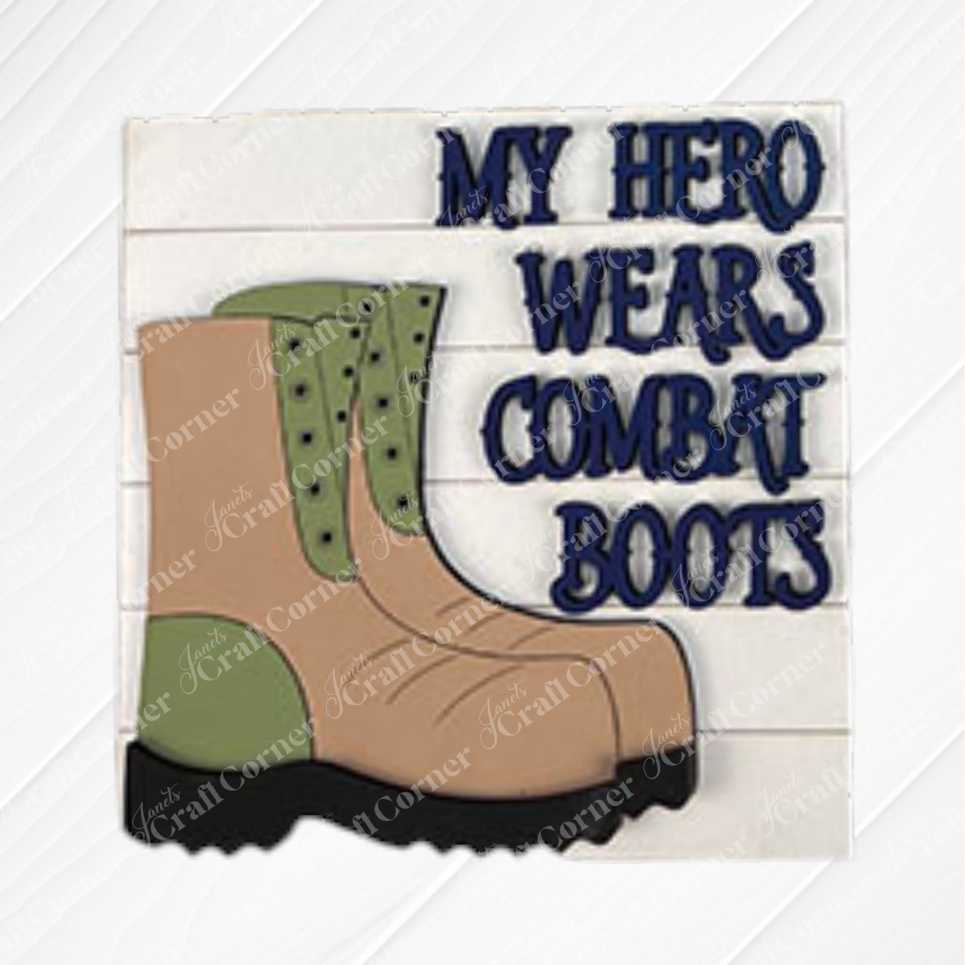 A drawing of a tan and green combat boot appears next to bold blue text saying "My Hero Wears Combat Boots" on white wood—an ideal accent or addition to your Military Squares collection by Janet's Craft Corner.