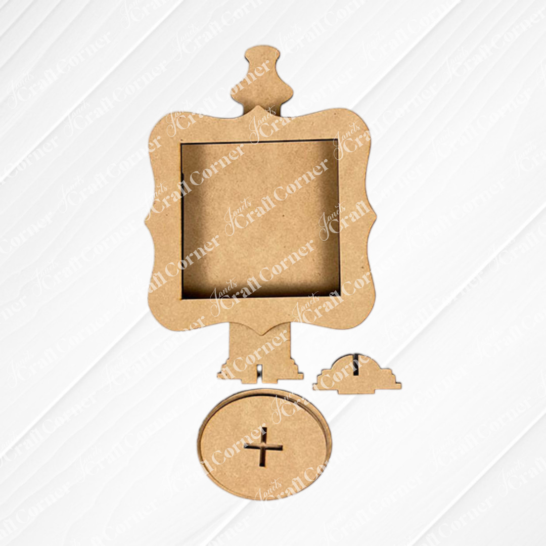The Heartland Drop In Swappable Squares Holder DIY Craft Kit (set of 1) features an unfinished wooden clock frame with a square opening, circular base, and small wooden hands—ideal for creative home décor, shown on a white textured background.