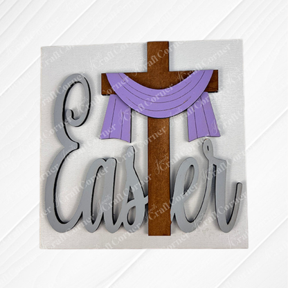 Janet's Craft Corner Religious Easter Squares feature a wooden cross with a purple cloth above “Easter” in large cursive gray letters on a white textured background—great for tiered tray decor or Swappable Squares displays.